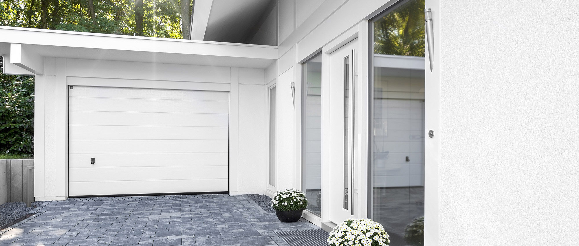 Maison individuelle moderne avec garage blanche, allée pavée et entrée avec vitrage