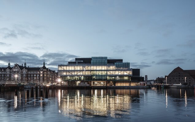 Bâtiment illuminé au bord de l'eau au crépuscule
