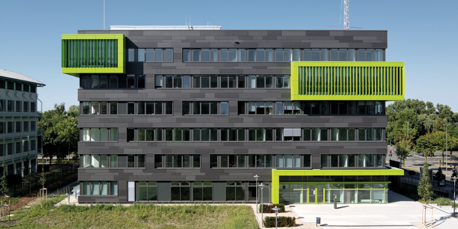 Bâtiment universitaire moderne gris avec des accents verts