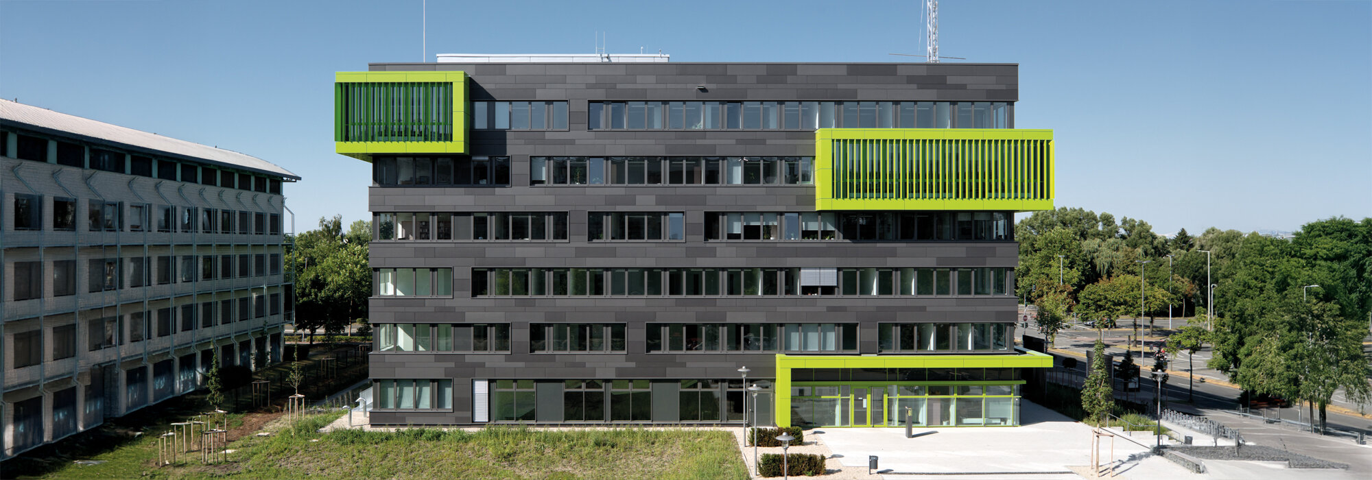 Bâtiment universitaire moderne gris avec des accents verts