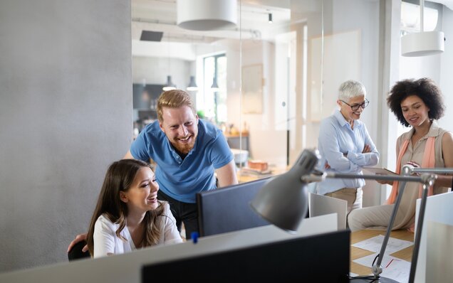 Réunion d'équipe dans un bureau moderne avec quatre personnes à leur poste de travail