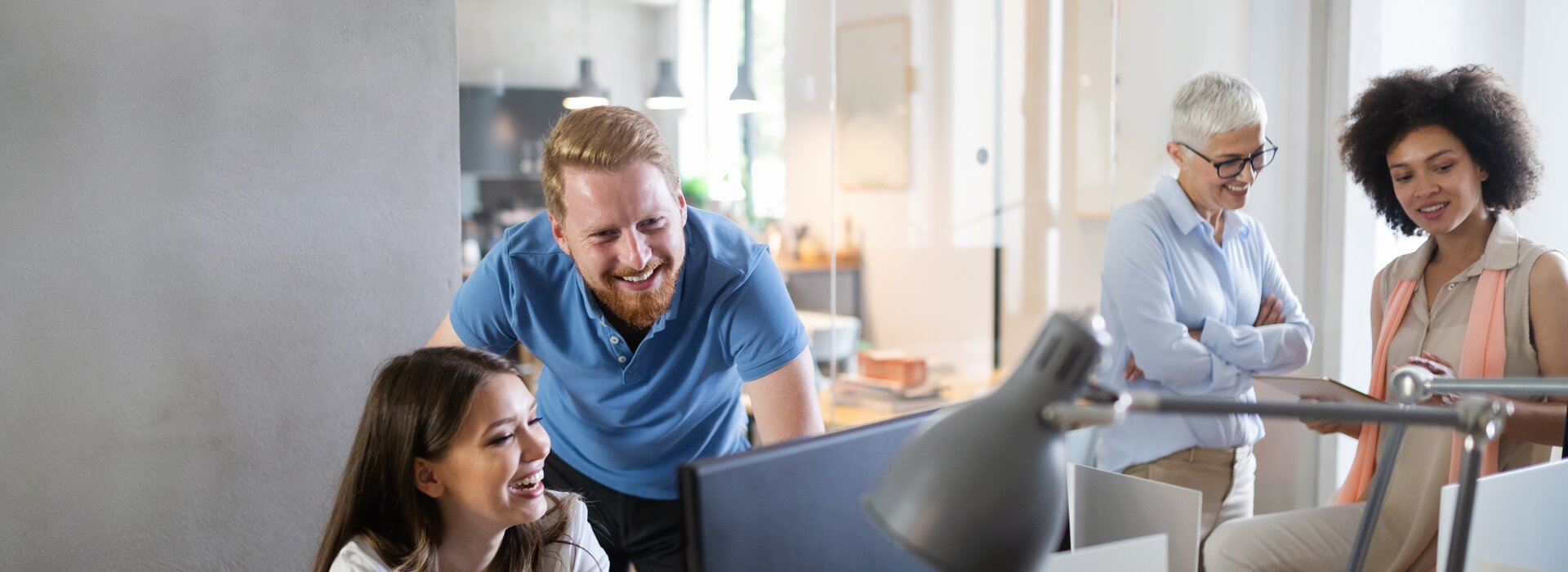 Réunion d'équipe dans un bureau moderne avec quatre personnes à leur poste de travail