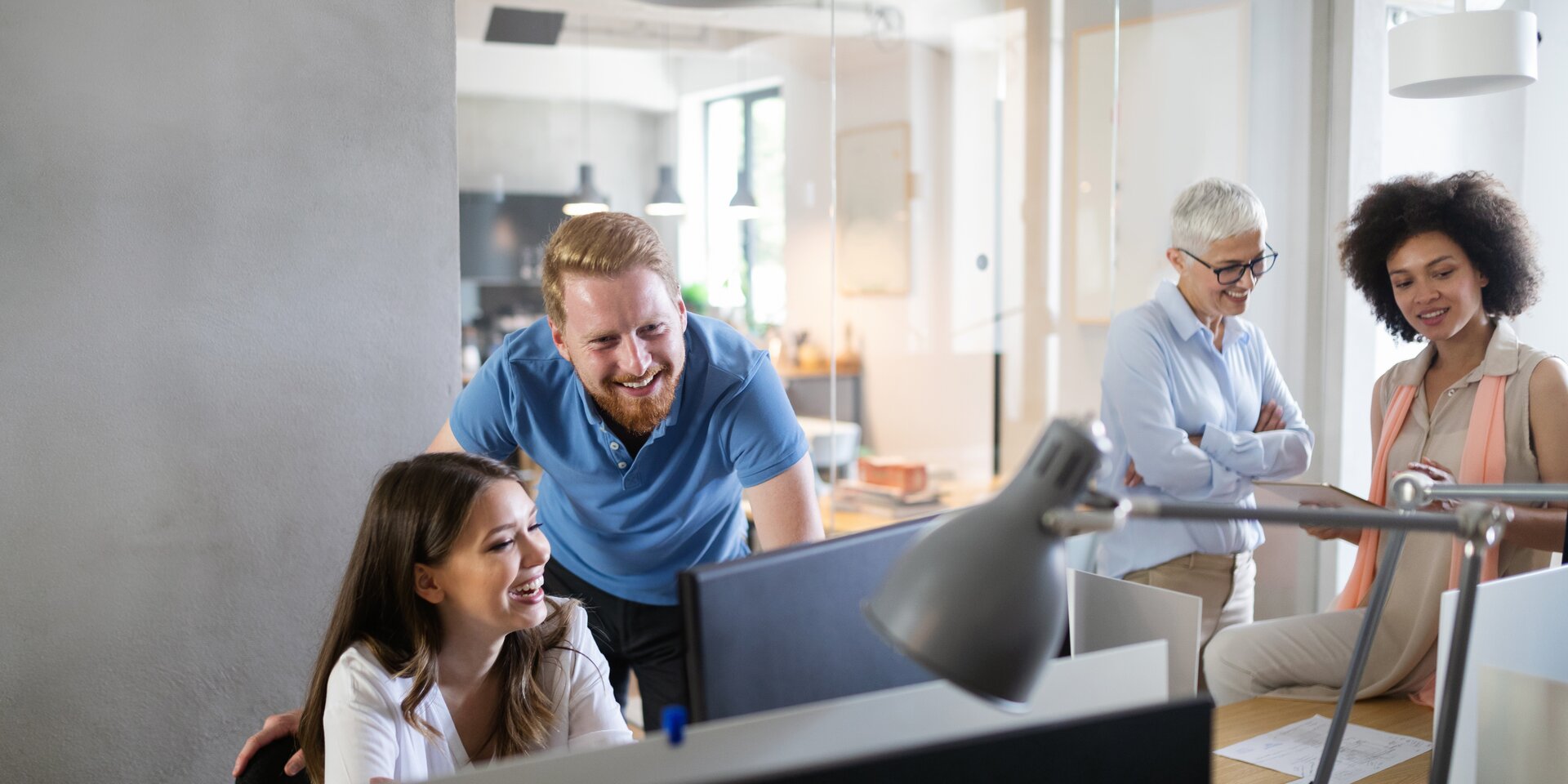 Réunion d'équipe dans un bureau moderne avec quatre personnes à leur poste de travail